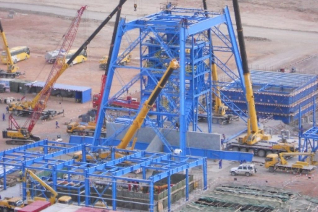 A large blue structure with several cranes in the background.