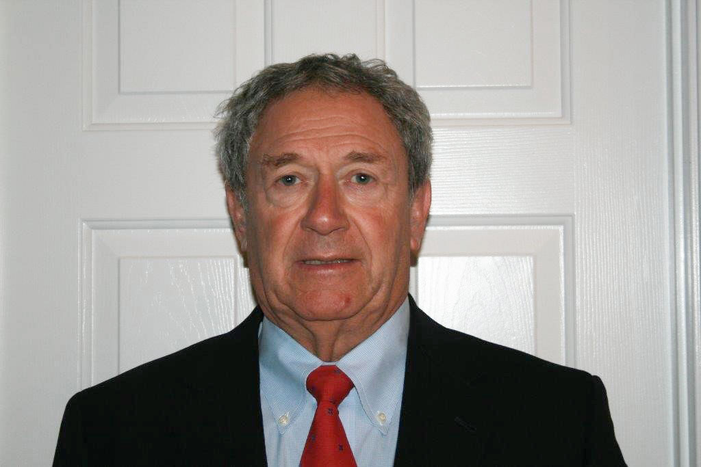 A man in a suit and tie standing next to a wall.